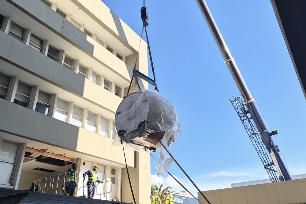 An MRI magnet, hoisted and delivered to site by an industrial crane.